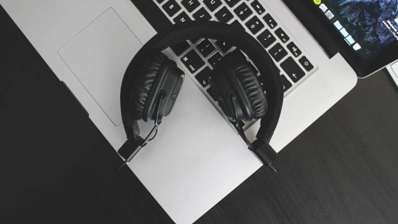 A sales rep wearing a headset works a call list on a laptop on a busy open-plan sales floor.