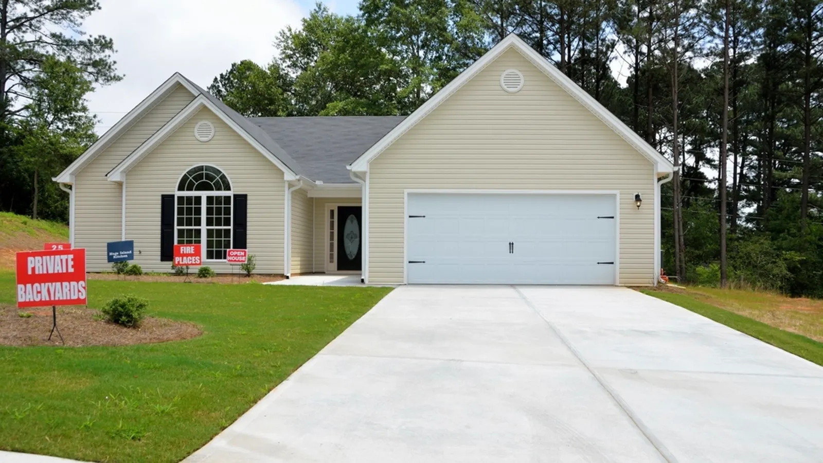 A suburban house with several real estate yard signs on the lawn.