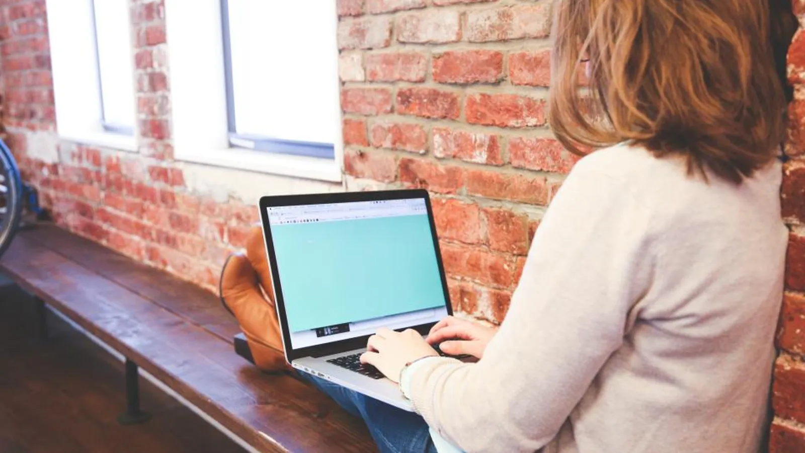A salesperson at a desk in the early evening typing a follow-up email on a laptop next to handwritten call notes.