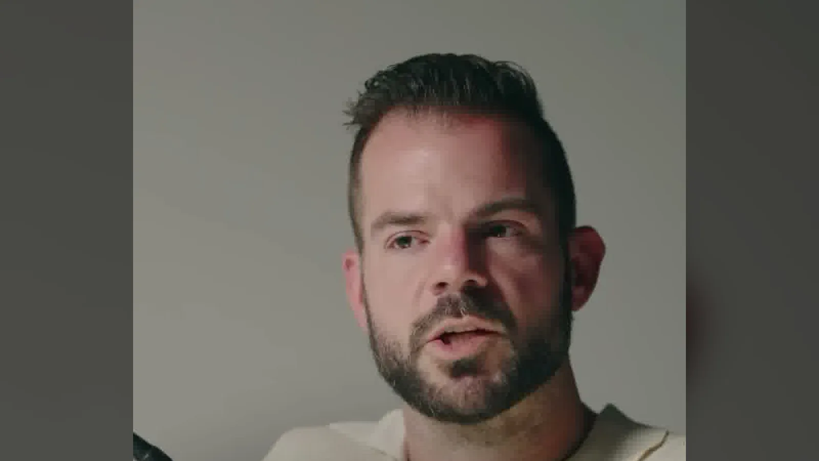 Cole Gordon in a cream shirt talking about his Instagram clips on his podcast set.